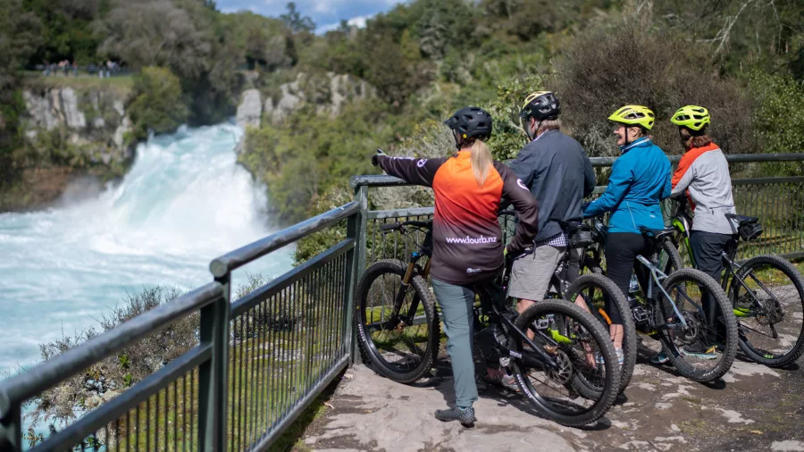 Group of cyclists admiring the power of Huka Falls on an e-bike tour