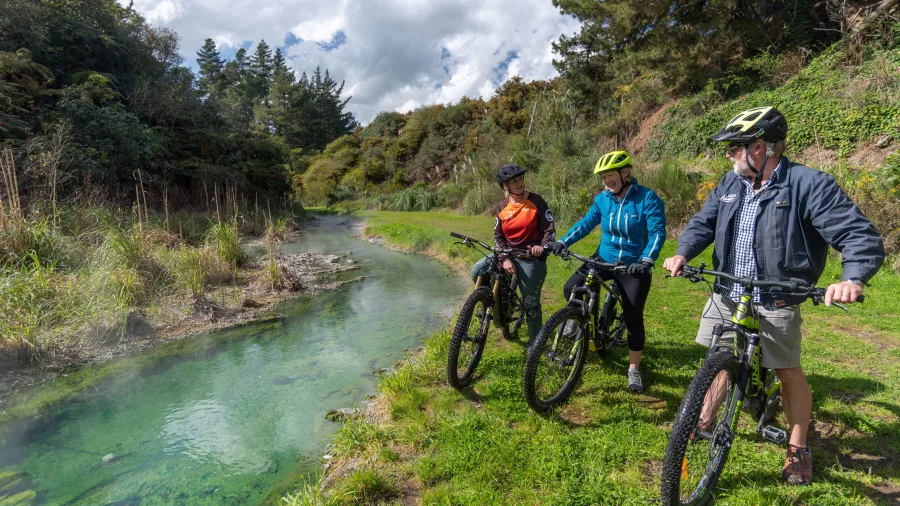 Cyclists stopping beside a geothermal stream on the Waikato River trail