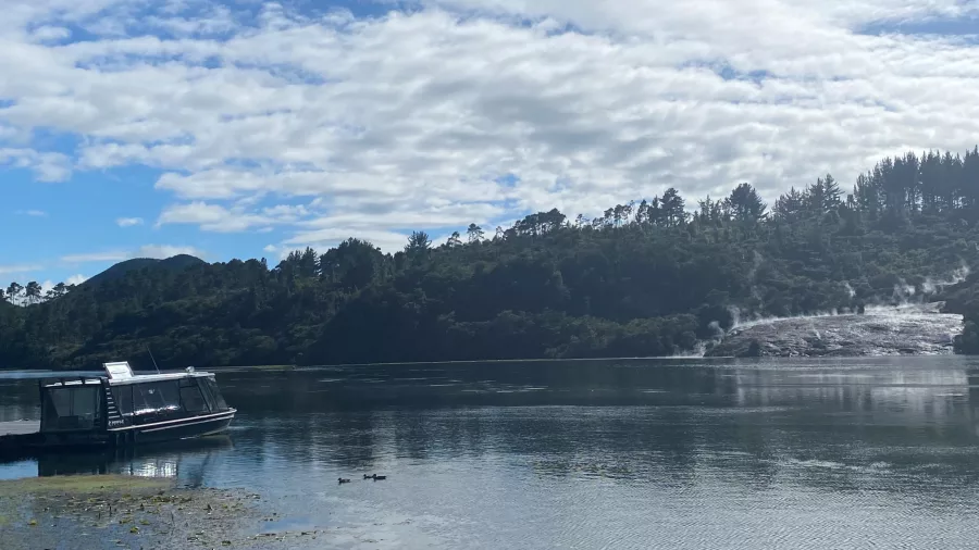 Tour boat moored at the Orakei Korako jetty on Lake Ohakuri under a cloudy blue sky