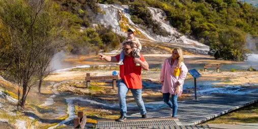 Family walking past Rainbow Terrace signpost in Orakei Korako geothermal park