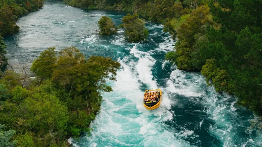 Aerial view of a yellow Rapids Jet boat navigating the Waikato River rapids near Taupō, surrounded by native forest.