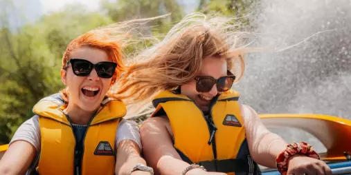Two women enjoying the thrill of a Rapids Jet ride near Taupō, with water spraying and hair blowing in the wind.