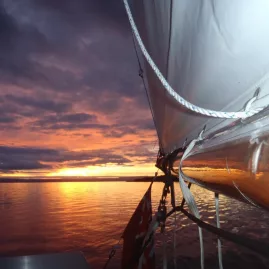 Sailing boat on Lake Taupō at sunset with glowing skies and sail rigging in view