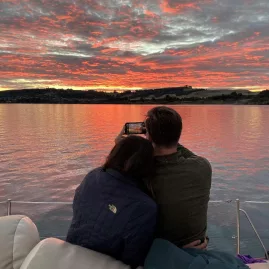 Couple watching the sunset and taking a photo during a Sail Barbary cruise on Lake Taupō