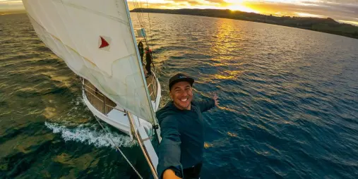 Man taking a selfie on the bow of Sail Barbary during a sunset cruise on Lake Taupō
