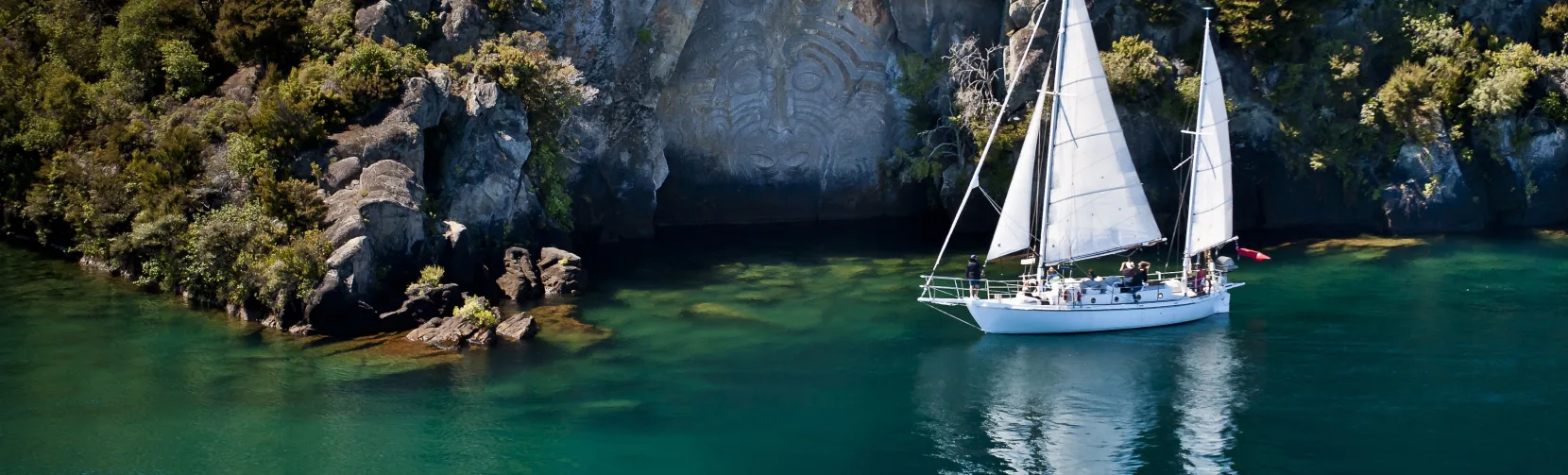 Sail Barbary anchored at Mine Bay in front of the Māori Rock Carvings on Lake Taupō
