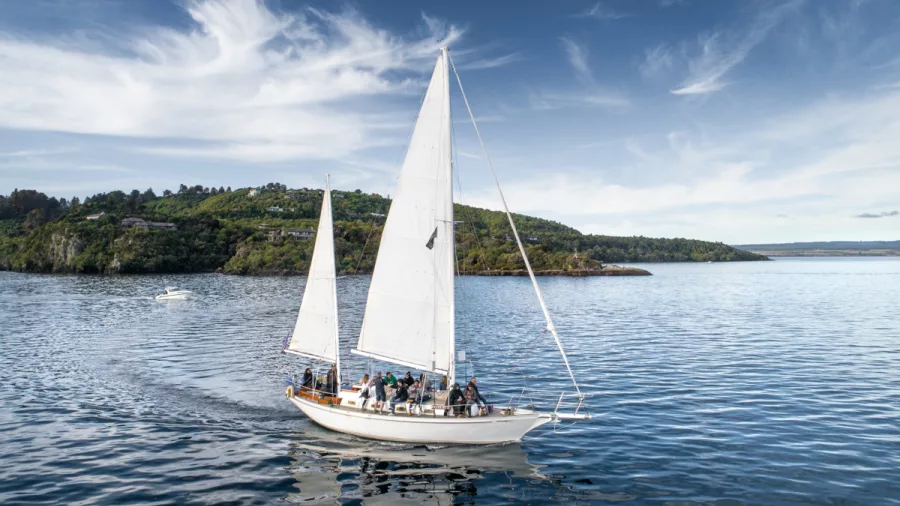 Sail Barbary boat gliding through calm bays on Lake Taupō under soft skies