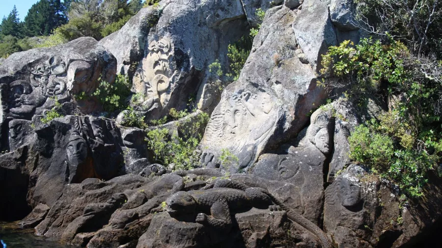 Detailed carvings of faces and a lizard at Mine Bay on Lake Taupō