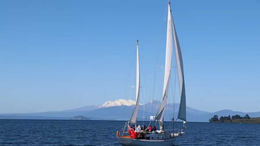 Sail Barbary gliding under full sail on Lake Taupō with snowy mountains in the distance
