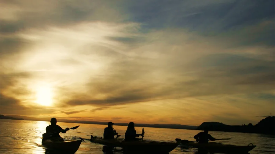 Group of kayakers silhouetted against a glowing Lake Taupō sunset