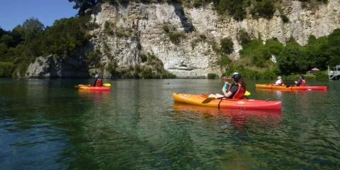 Group of kayakers paddling near white cliffs on the Waikato River in Taupō under clear blue skies