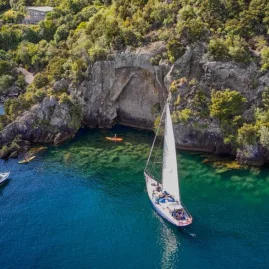 Sailboat and kayakers near the Mine Bay Māori Rock Carvings on Lake Taupō