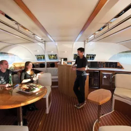 Guests relaxing in the saloon of a Pure Cruise sailing yacht on Lake Taupō