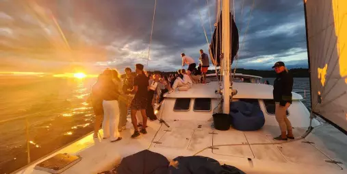 Guests enjoying a vibrant sunset aboard Tiua on Lake Taupō