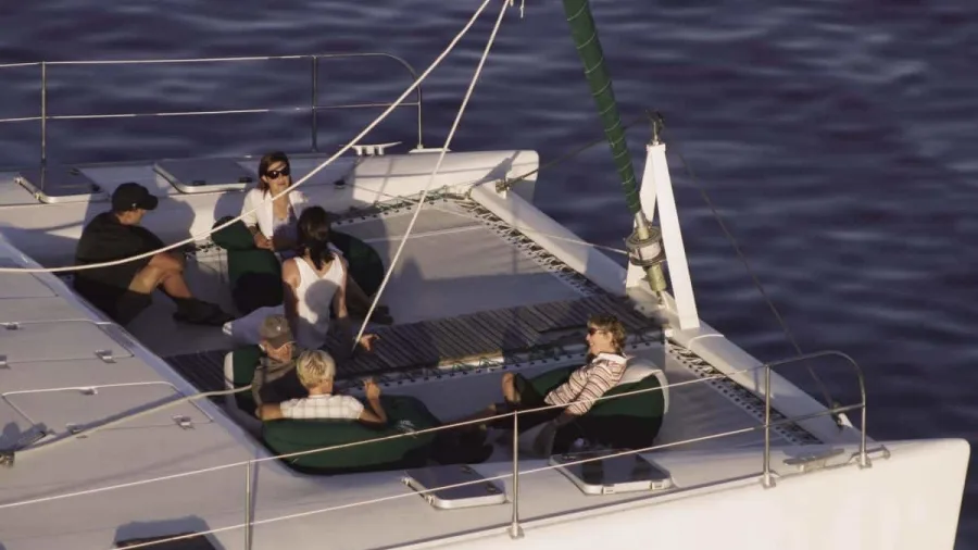 Guests relaxing on the front deck of the Tiua catamaran on Lake Taupō at sunset