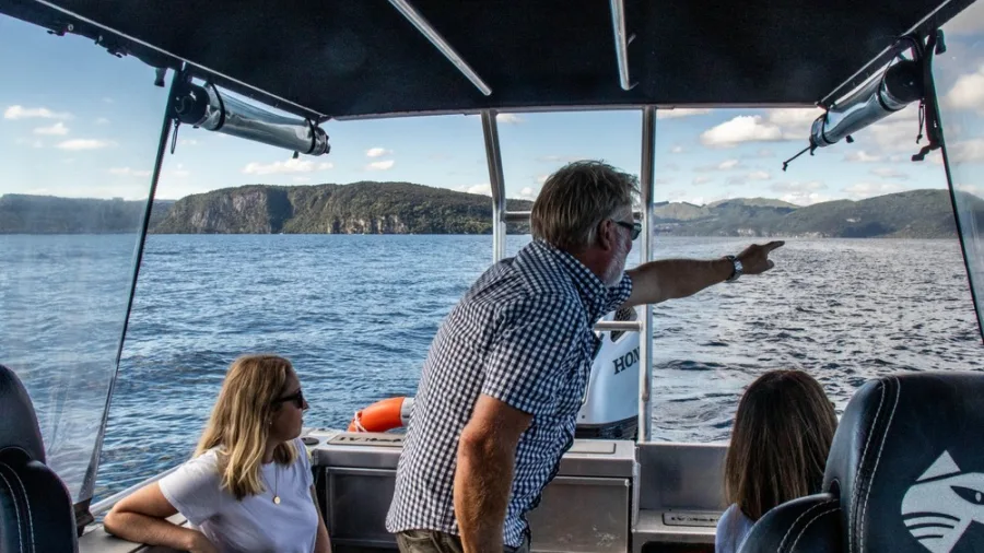 Boat guide pointing across Lake Taupō while guests look out at the view