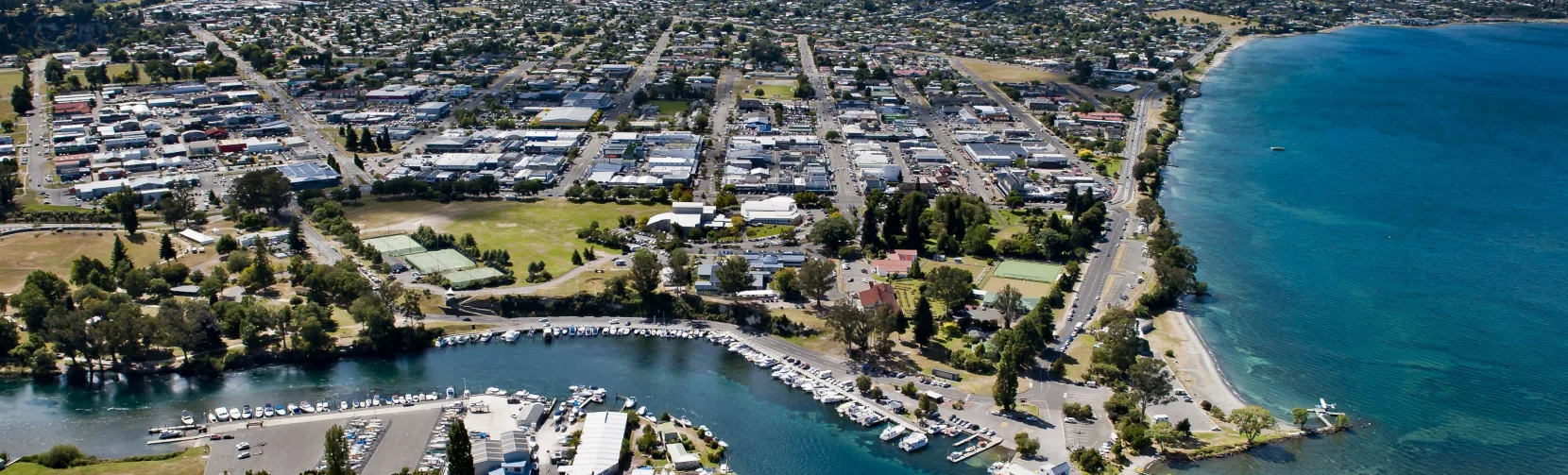 Aerial view of Taupō Boat Harbour, town centre, and Mount Tauhara beside the shores of Lake Taupō in New Zealand.