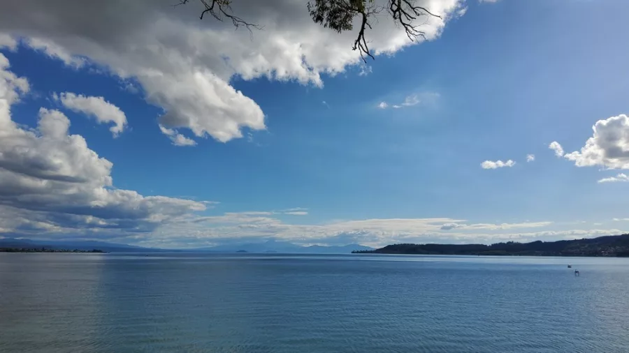 Expansive view over Lake Taupō with calm blue waters, distant hills, and dramatic skies in New Zealand’s North Island