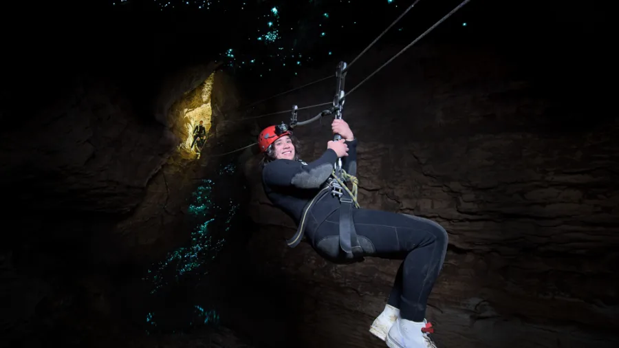 Adventurer ziplining through glow worm-lit cave on the Black Abyss tour in Waitomo