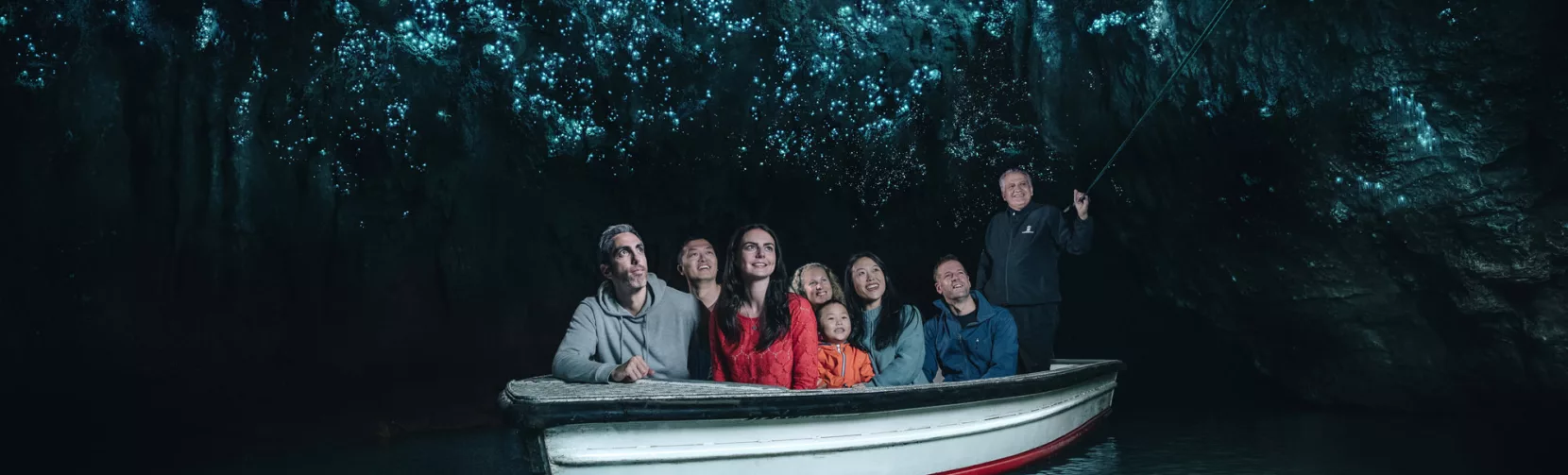 Visitors on a guided boat ride through the glowworm-lit cave at Waitomo, New Zealand