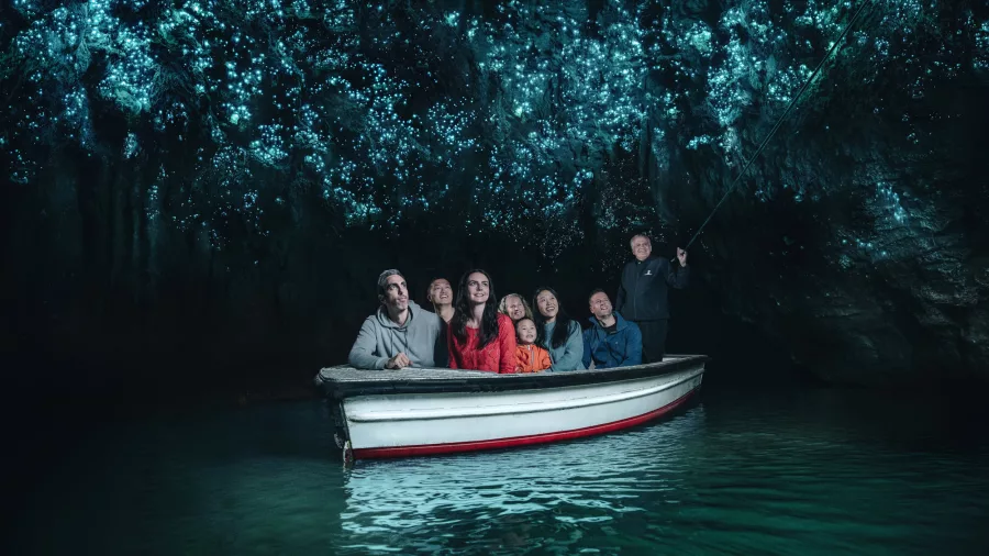 Visitors on a guided boat ride through the glowworm-lit cave at Waitomo, New Zealand