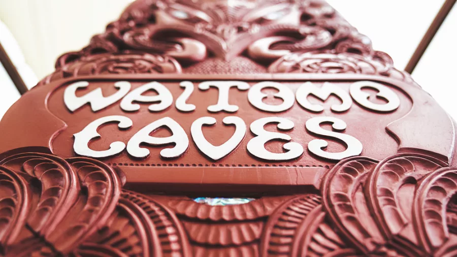 Close-up of a traditional Māori carving featuring the Waitomo Caves sign at the entrance in New Zealand.