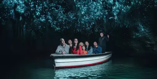 Visitors on a guided boat ride through the glowworm-lit cave at Waitomo, New Zealand