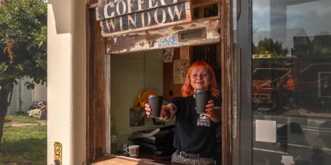 Barista serving takeaway coffee at the window of Raumati Social Club on the Kapiti Coast, New Zealand