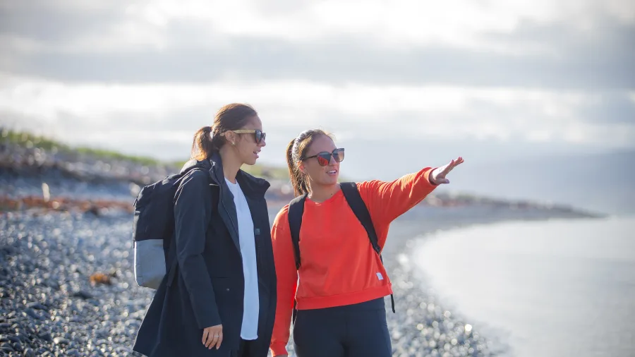 Two women walking along the shore of Kapiti Island, Wellington Region, New Zealand