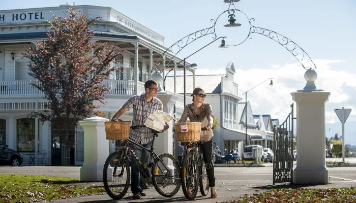 Couple cycling through Martinborough town square with map