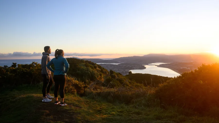 Couple watching the sunrise from Mt Rangituhi with views over Porirua