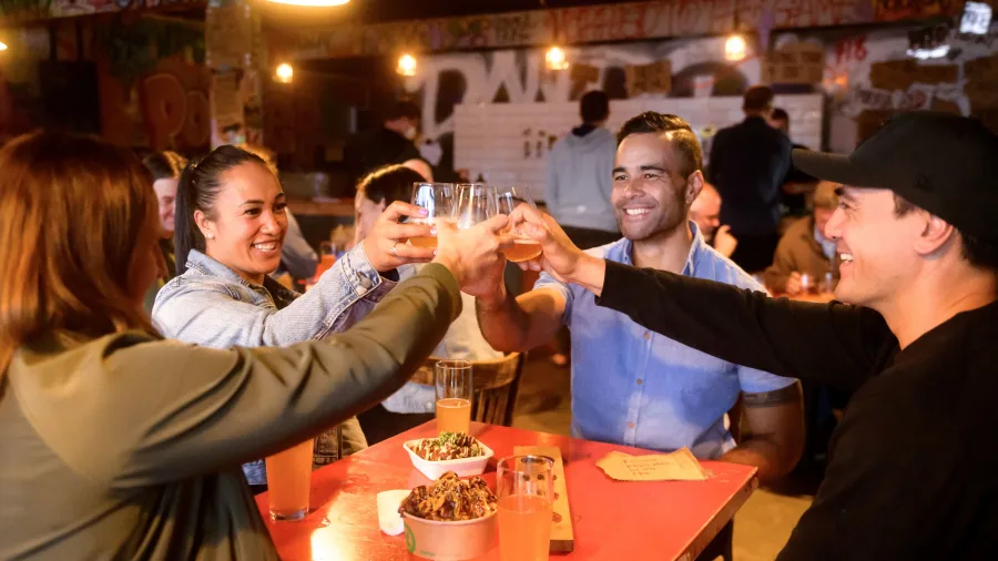 Friends toasting craft beer inside Abandoned Brewery, Porirua