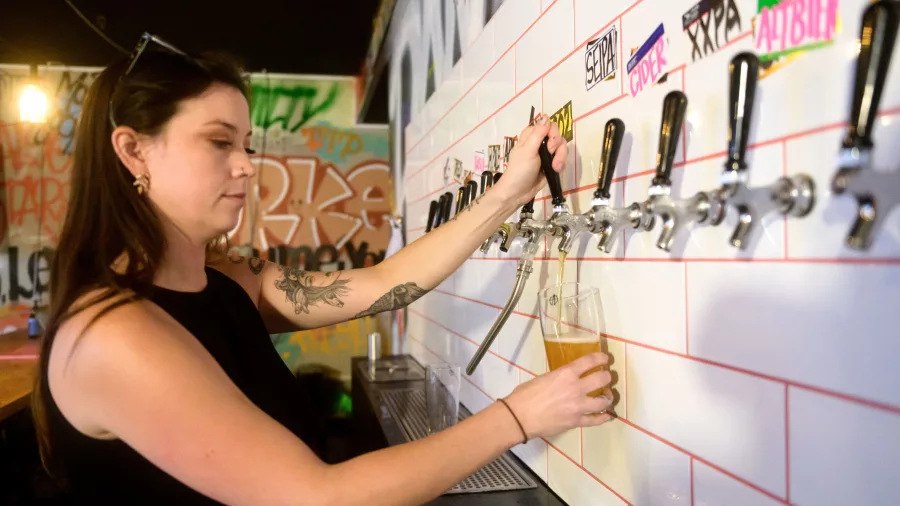Woman pouring craft beer from tap at Abandoned Brewery in Porirua