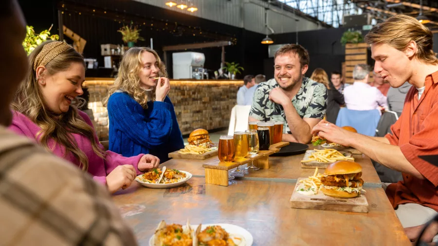 Friends enjoying burgers, fries, and craft beer at Brewtown in Upper Hutt, Wellington