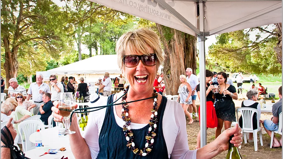 Woman smiling with a wine glass and bottle at Wairarapa Wines Harvest Festival