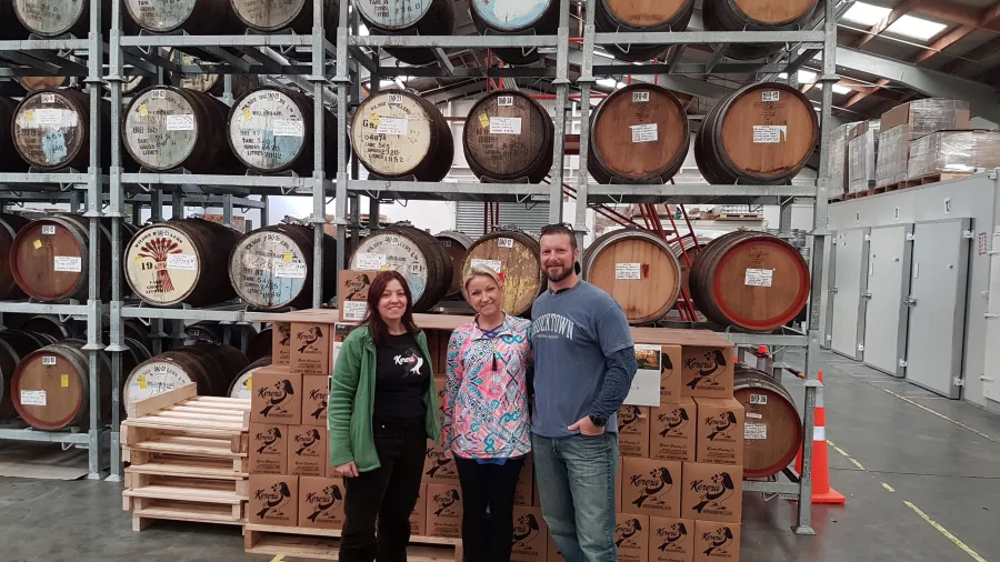 Guests standing in front of stacked oak barrels and cartons at Kereru Brewing during a craft beer tour