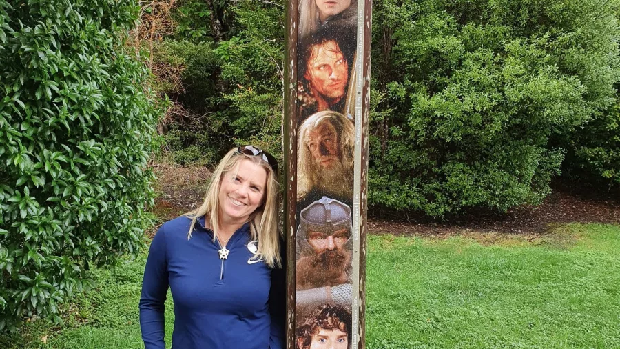 Woman poses beside the Lord of the Rings height meter at Rivendell filming location