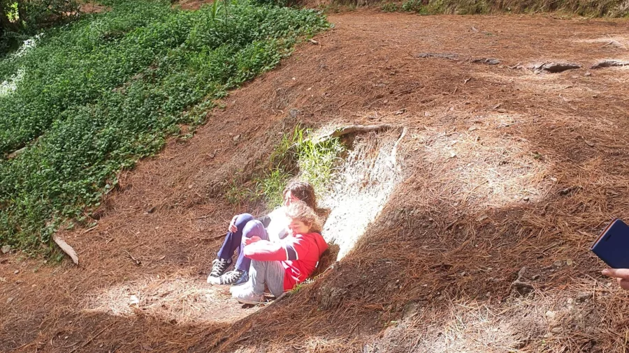 Two kids sit in a sunlit hollow at Hobbits Hideaway from The Lord of the Rings