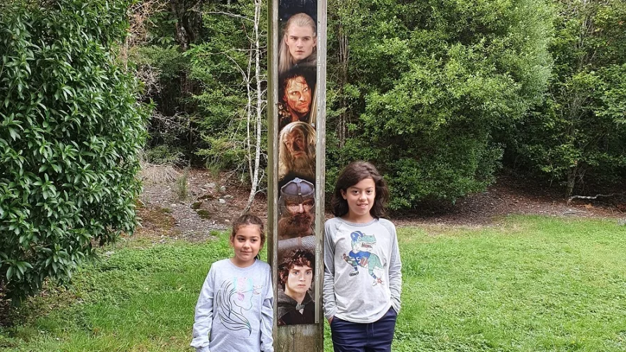Two kids standing beside the height comparison post of Lord of the Rings characters at Rivendell