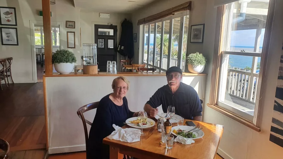 Couple dining by the window at Lake Ferry Pub with ocean views in the background