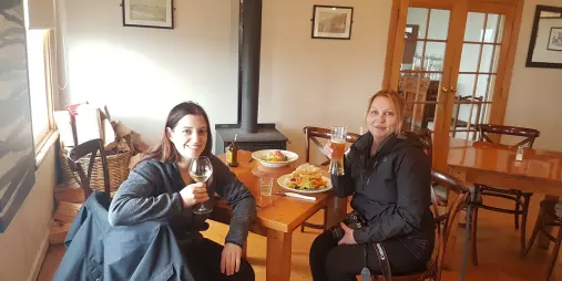 Two women enjoying a drink and hearty lunch inside the Lake Ferry Hotel