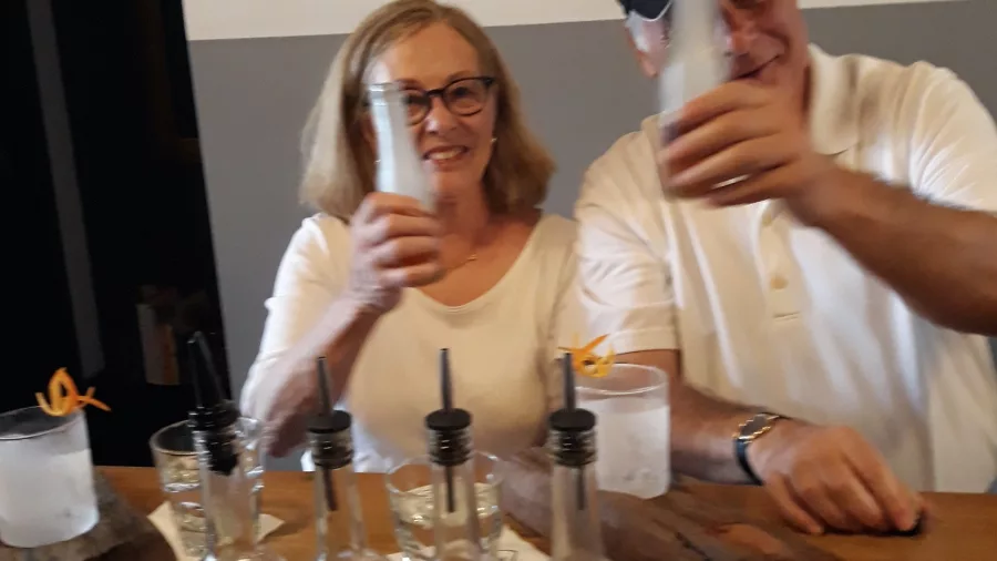 Two smiling guests shaking cocktails at a bar during a hands-on mixology experience in Wellington