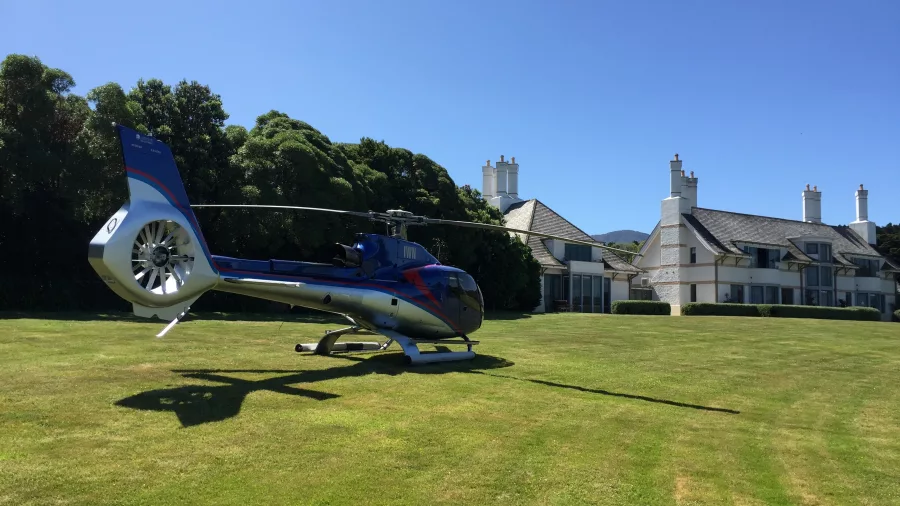 Helicopter parked on the lawn of Wharekauhau Country Estate on a sunny day