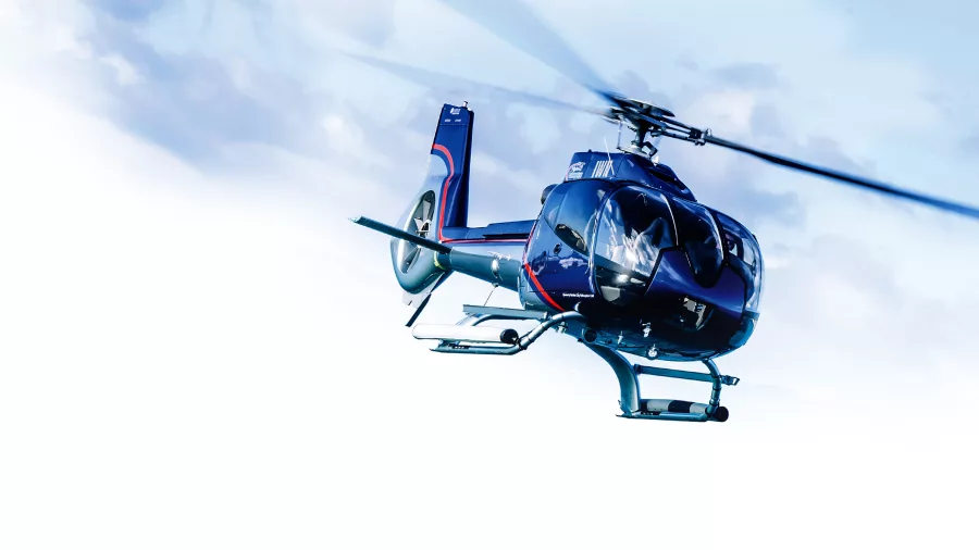 Helicopter mid-flight against a bright sky with motion blur on the blades