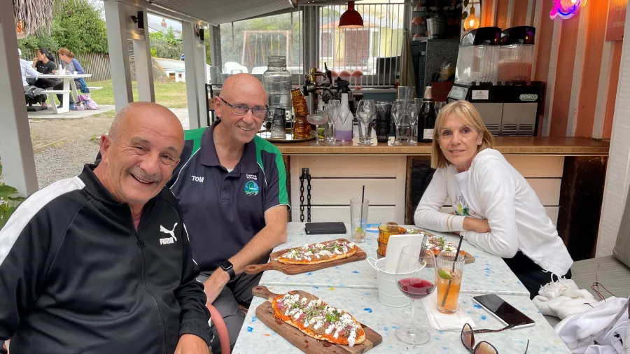 Three visitors enjoying flatbreads and drinks at Hey Coastie Cafe in Waikanae Beach