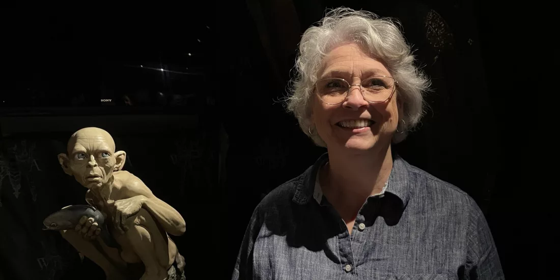 Visitor smiling beside Gollum statue holding a fish at Wētā Cave