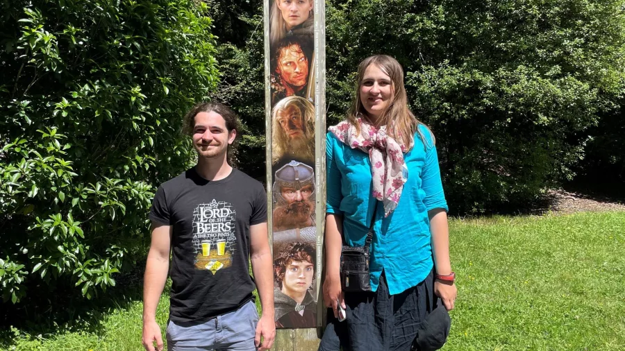 Visitors standing beside a film marker featuring Lord of the Rings characters at Rivendell in Kaitoke Regional Park