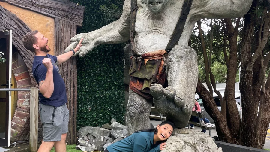 Two people posing dramatically with troll statue at Wētā Cave