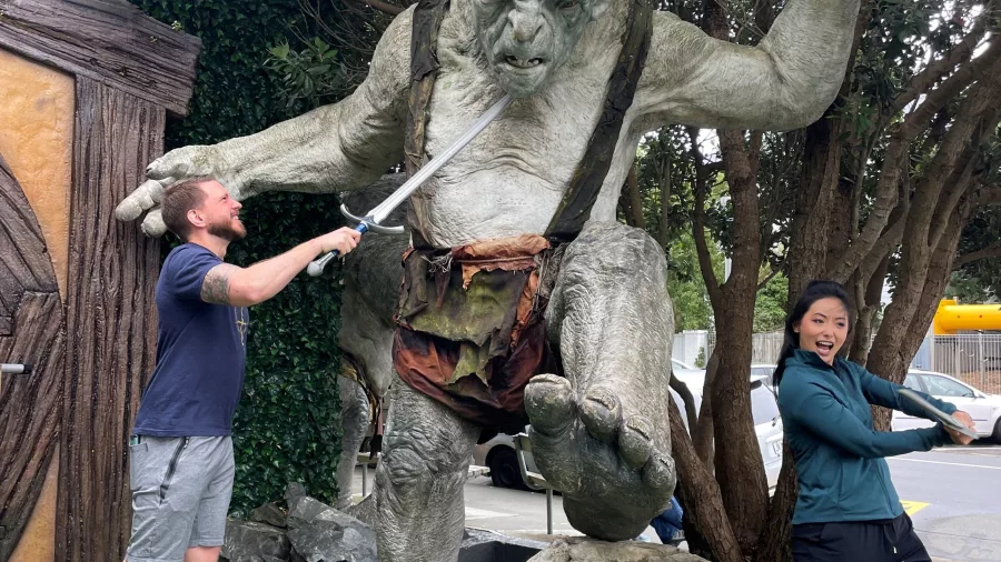 Visitors posing with troll statue at Wētā Cave, one holding a sword dramatically