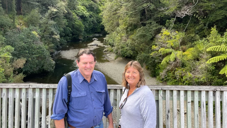 Couple standing on a wooden bridge overlooking the river at Kaitoke Regional Park, known as the Fords of Isengard filming location